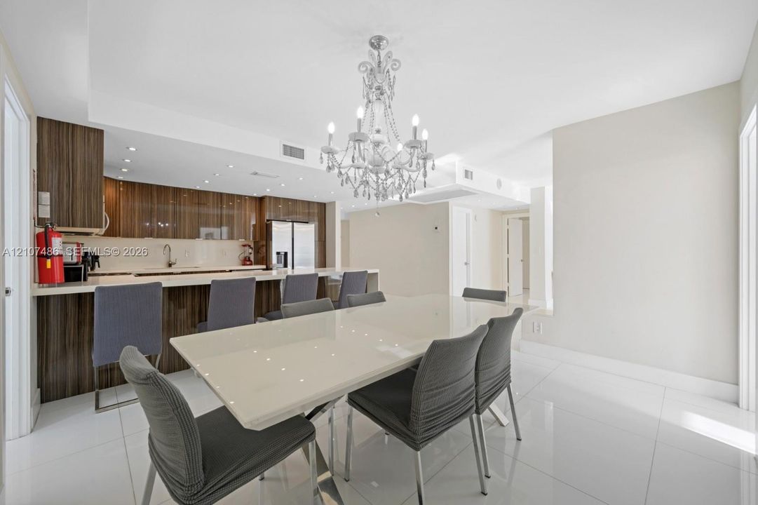 Kitchen featuring horizontal-grain wood cabinetry, integrated stainless steel appliances, and a breakfast bar with stone-surfaced countertops