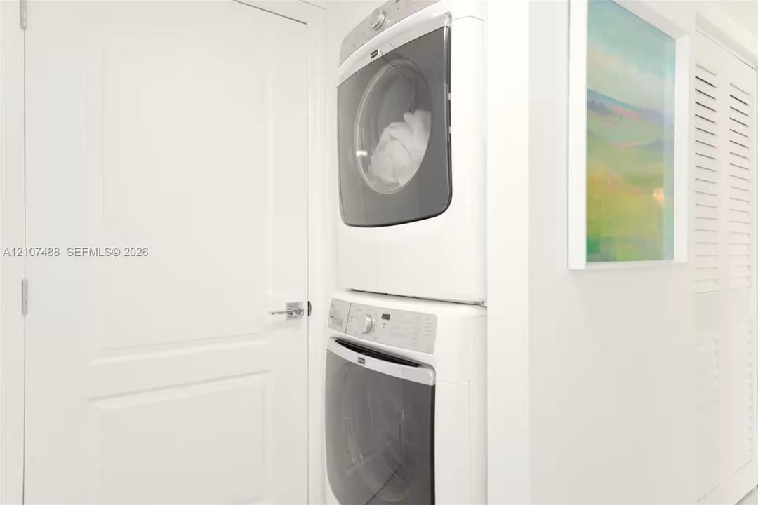 Stacked front-loading washer and dryer, solid core panel door with metallic hardware, and louvered closet door