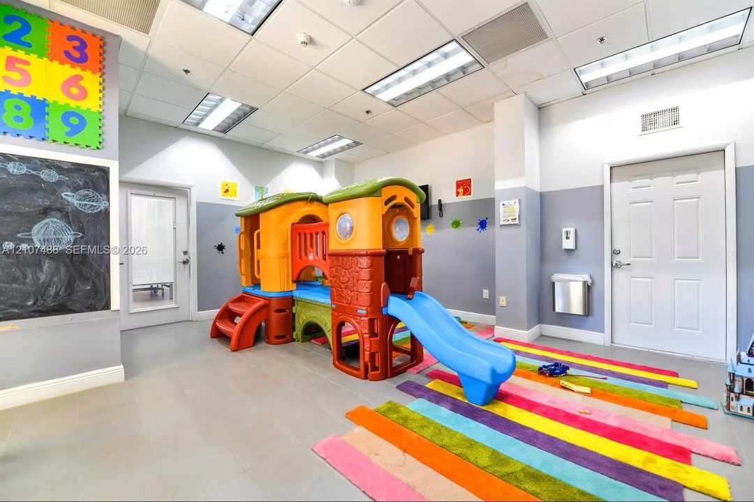 Spacious room featuring a drop ceiling with recessed lighting, smooth-finish tile flooring, a wall-mounted chalkboard, and multiple secure-locking doors