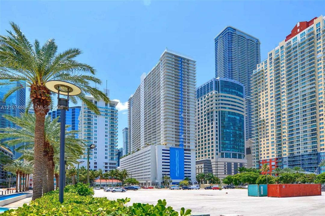 Urban high-rise architecture featuring glass facades, concrete exterior cladding, blue structural accents, and mature palm trees