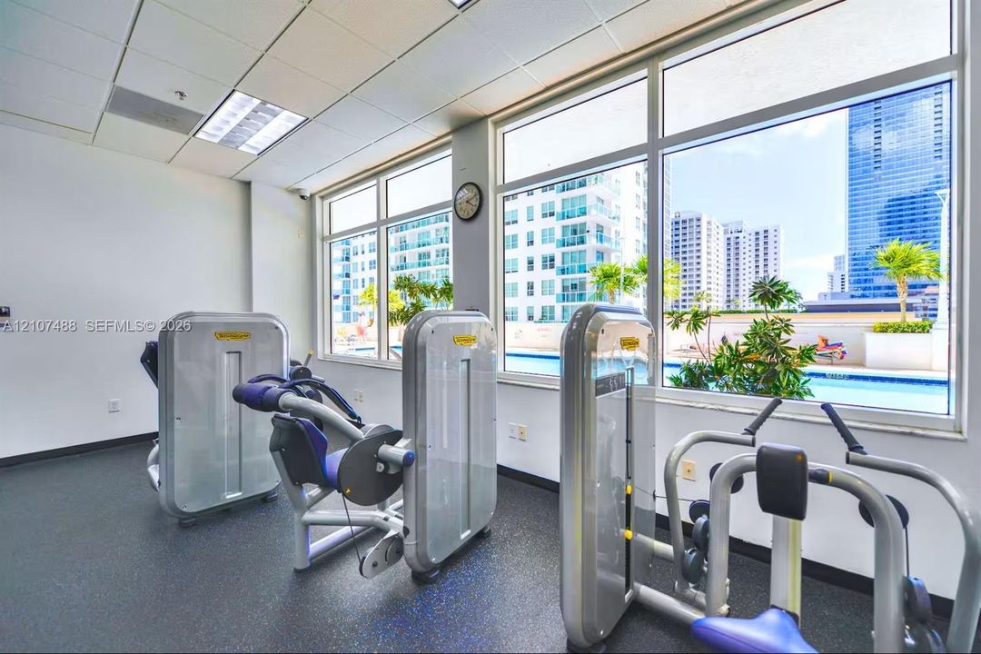 Fitness center featuring rubber flooring, oversized windows, and built-in exercise machines