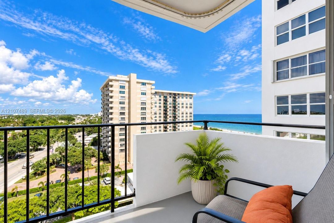 Private balcony featuring black metal railings, solid partition walls, and expansive ocean and coastal scenery