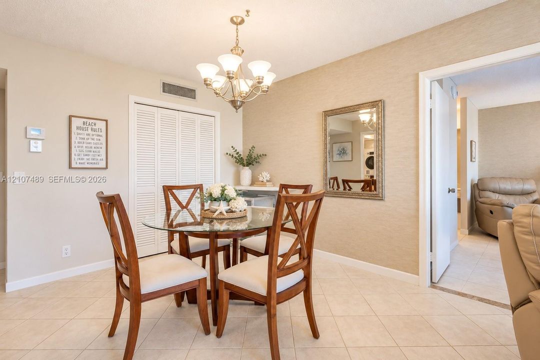 Dining area featuring textured wall finish, ceramic tile flooring, a multi-light metal chandelier, and a louvered-door storage closet