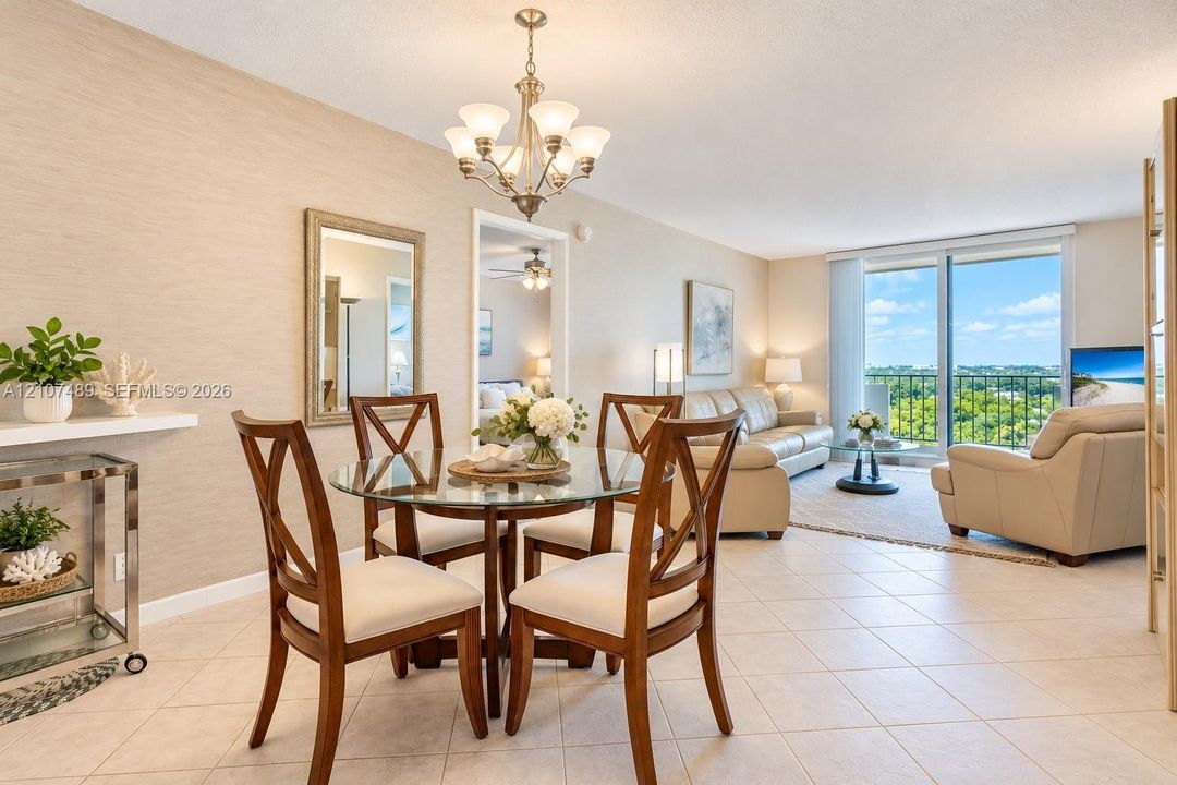 Open-concept space featuring neutral textured wall treatments, large-format tile flooring, a multi-arm chandelier, and floor-to-ceiling glass sliding doors