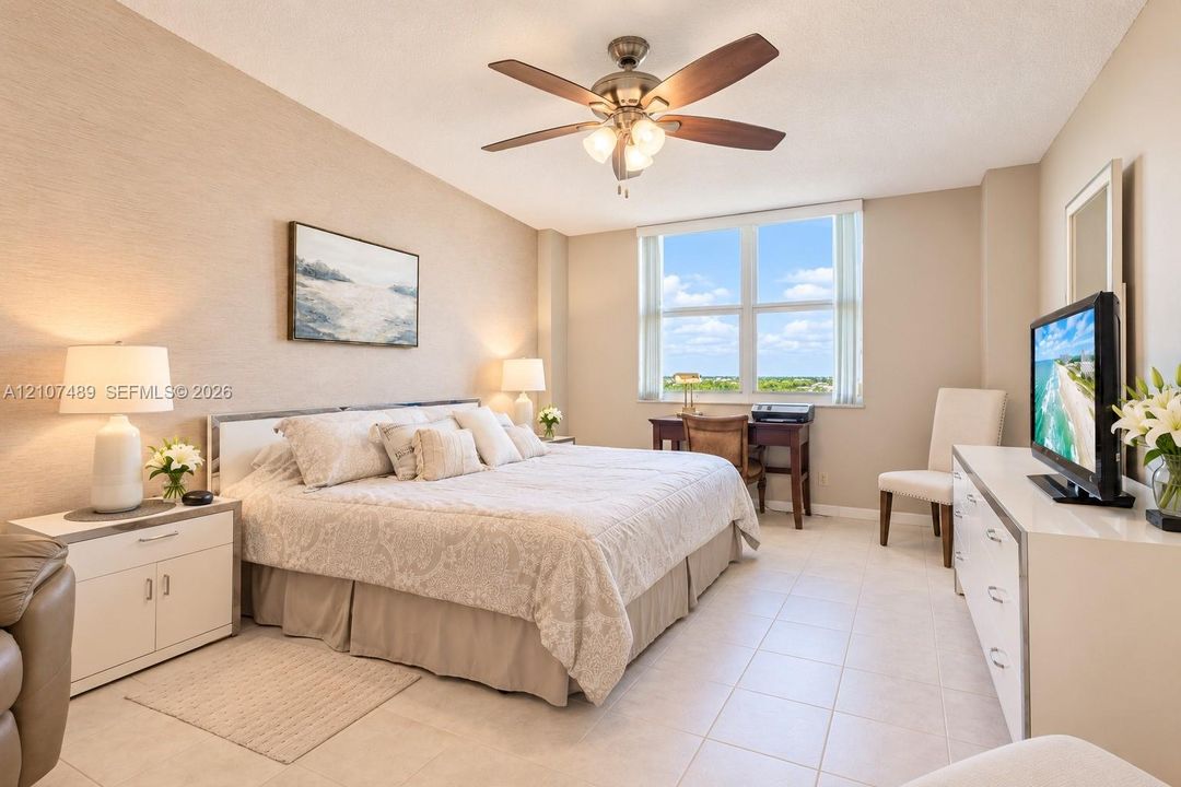Spacious interior featuring large windows, neutral wall finishes, tile flooring, and a ceiling fan with integrated lighting