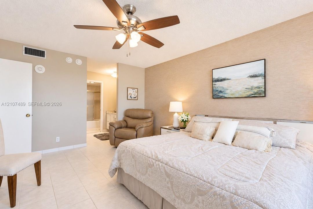 Spacious room featuring neutral tile flooring, a brushed-nickel ceiling fan with integrated lighting, and textured wall finish