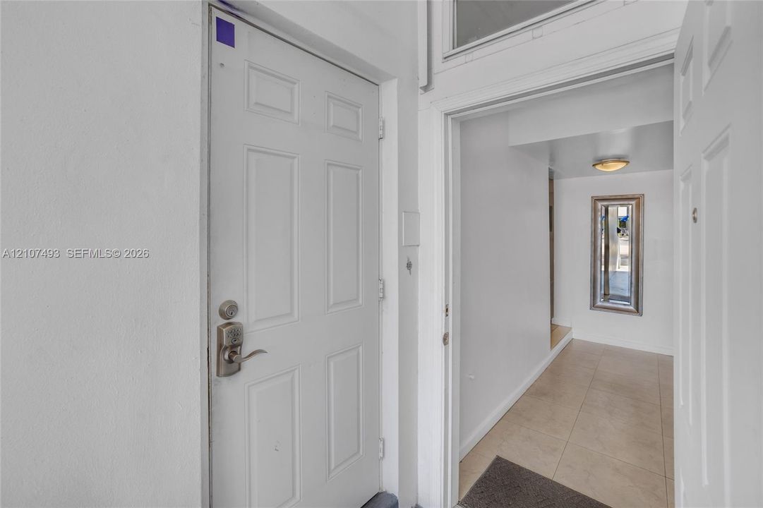 Main Apt, West side, Entrance, Hallway, door with satin nickel hardware, and neutral tile flooring