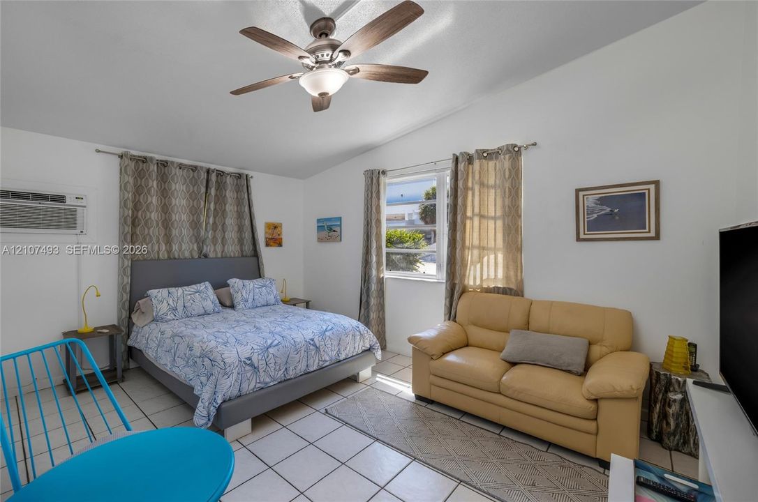 Studio 2 , East side, Living room and bedroom space featuring white tile flooring, a multi-blade ceiling fan with integrated lighting, and dual windows