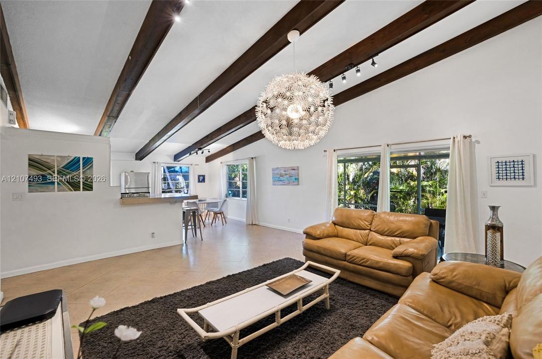 Main Apt, West side, Vaulted ceiling with exposed wood beams, tile flooring, large-scale pendant lighting, and oversized windows. Sliding Glass doors leading to screened patio.