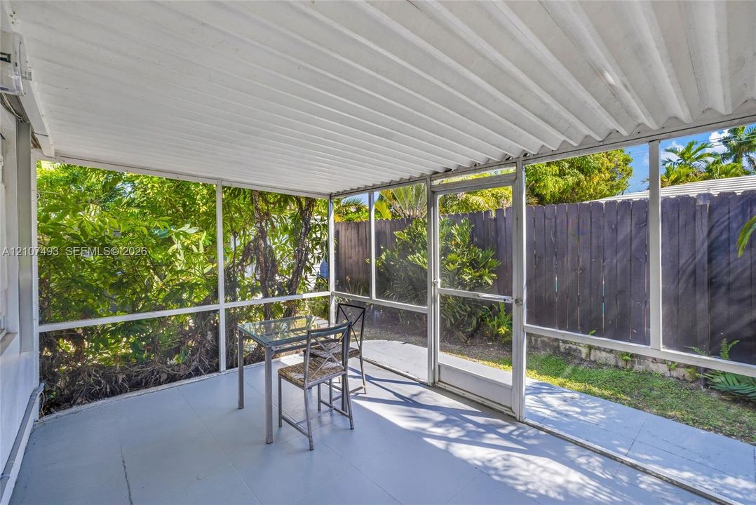 Main Apt , East side, Screened-in porch featuring a corrugated metal roof, aluminum framing, solid flooring, and a private wooden fence perimeter