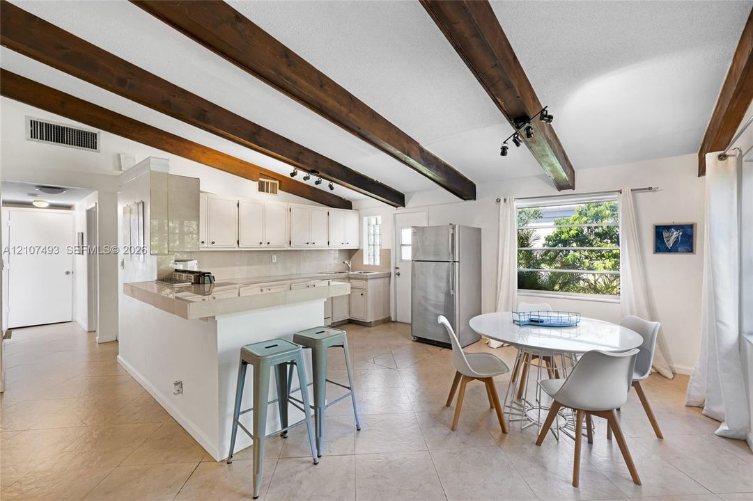 Main Apt, West side, Kitchen area, Exposed dark wood ceiling beams, tile flooring, white cabinetry, integrated peninsula, and track lighting
