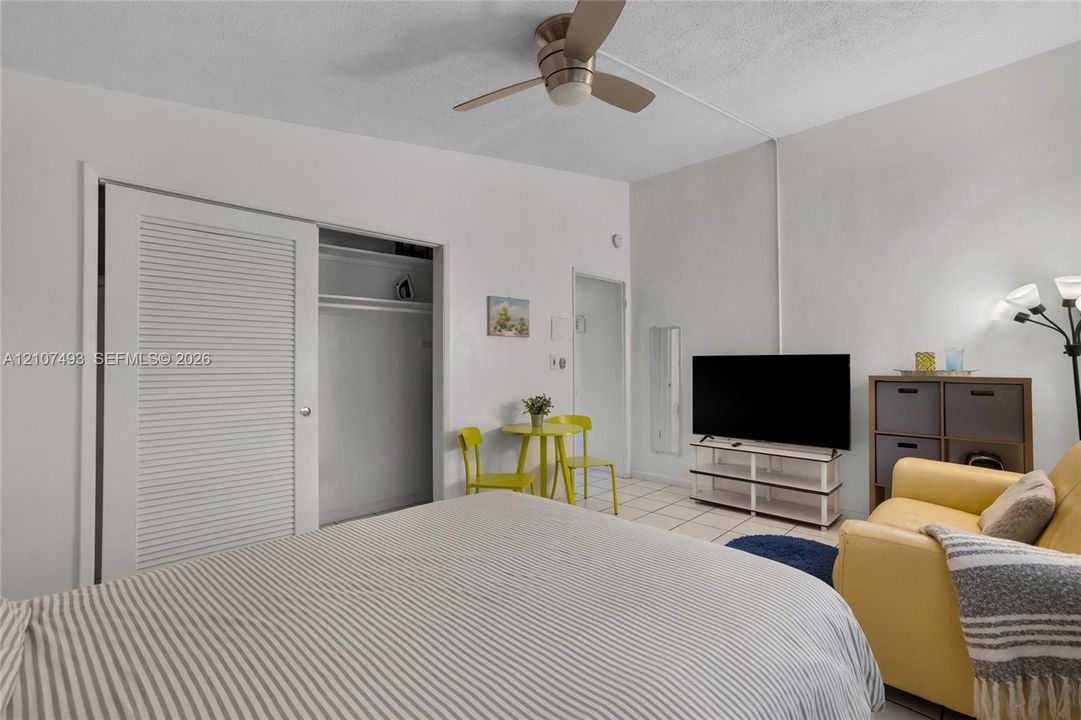 Studio 1 Room featuring neutral-toned walls, tile flooring, a ceiling fan with integrated lighting, and a closet with louvered doors