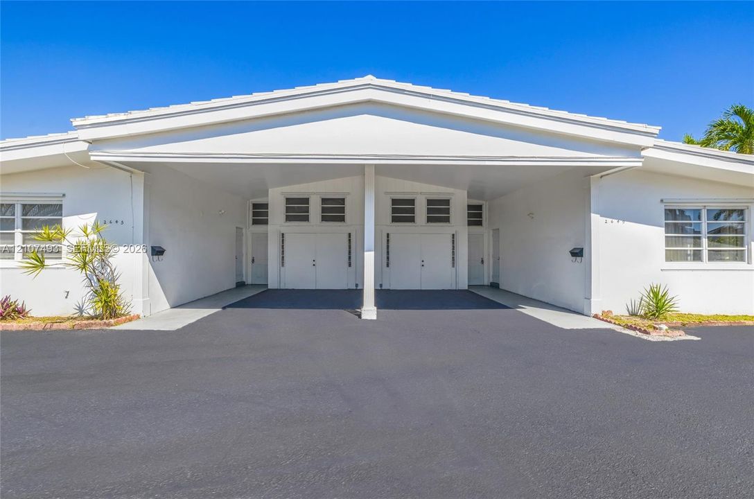 Front of Property, Single-story exterior featuring white stucco siding, a covered central carport, multi-pane windows, and glass block accents