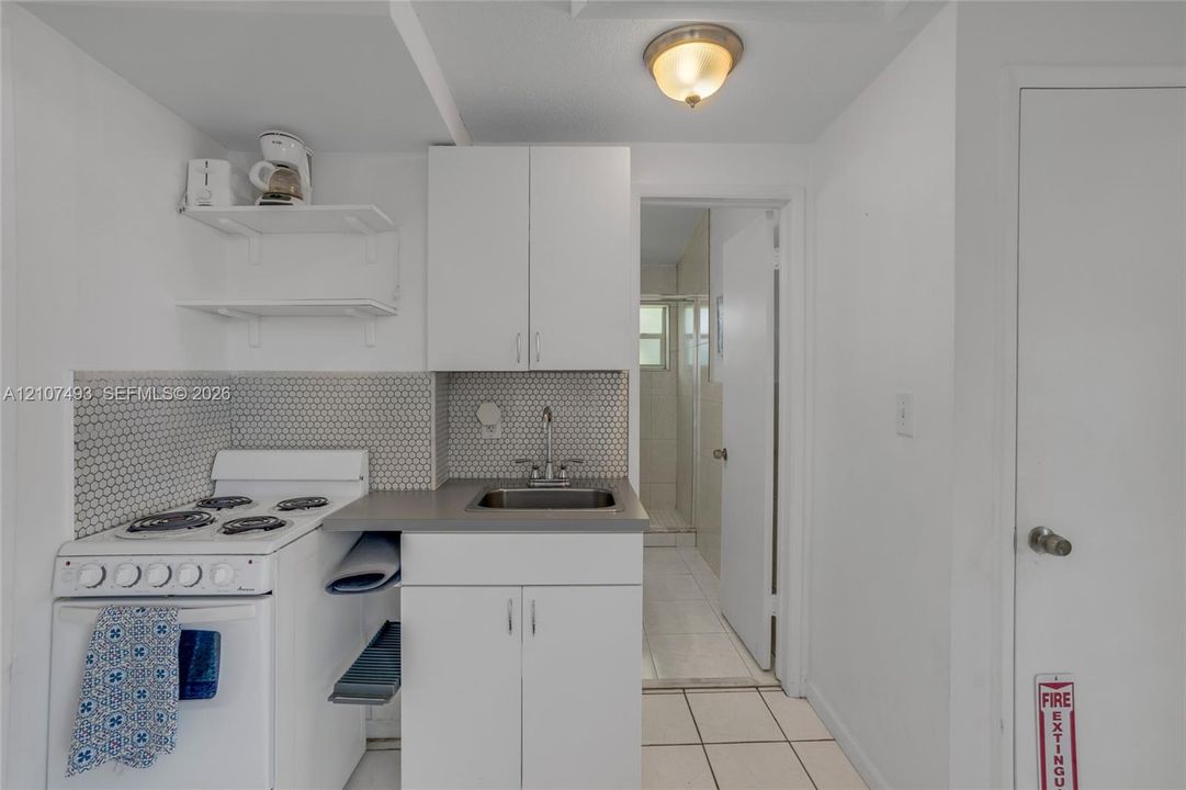 Studio 2, East side, Kitchenette featuring white cabinetry, a neutral-toned countertop, a hexagonal tile backsplash, a white four-burner gas range, and a drop-in sink