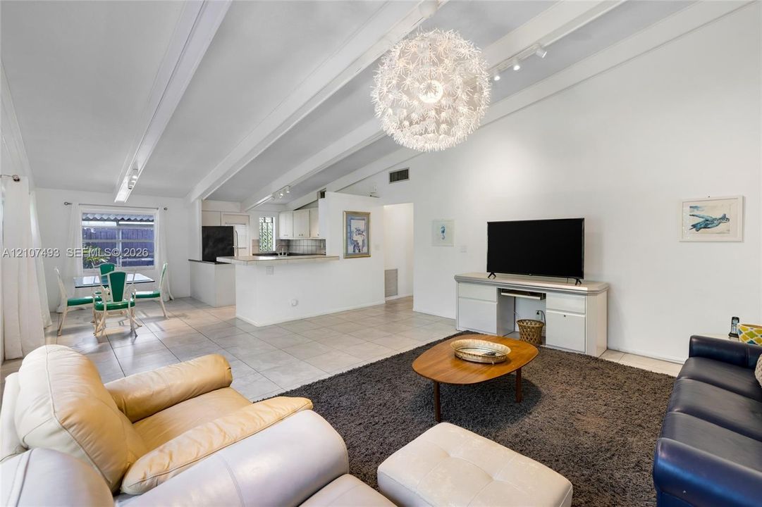 Main Apt, East side, Vaulted ceilings with exposed structural beams, tile flooring, large spherical pendant light fixture, and built-in cabinetry