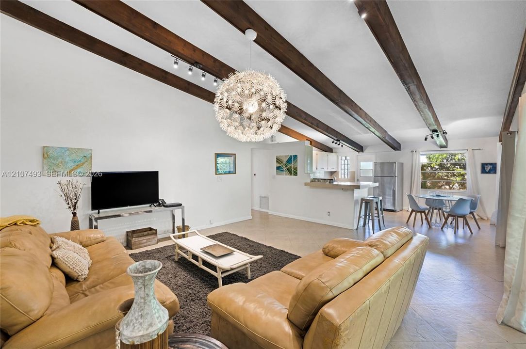 Main Apt, West Side, Living area, dining area, Vaulted ceilings featuring exposed wood beams, a contemporary sputnik-style chandelier, track lighting, and tile flooring