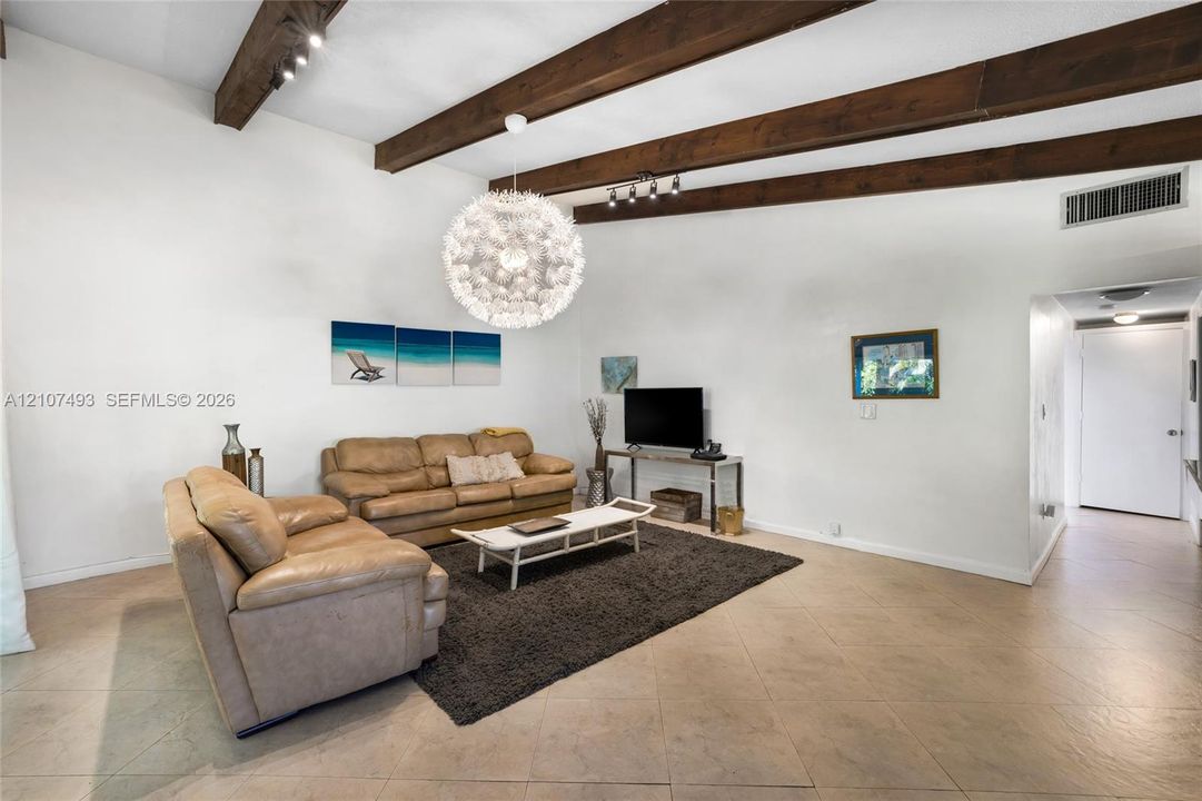 Vaulted ceiling with exposed wood beams, tile flooring, and a spherical statement pendant light fixture