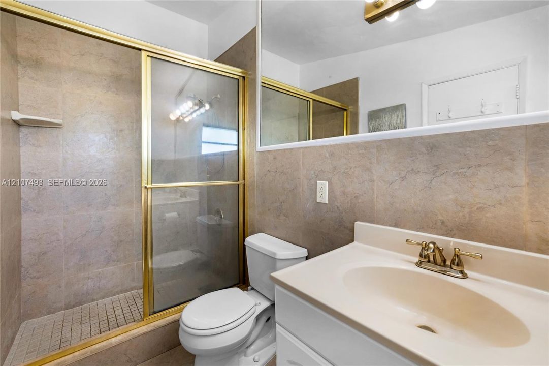 Main Apt, West side, Bathroom featuring a shower stall with a glass door, tile surround, vanity with an integrated sink, and a wall-to-wall mirror