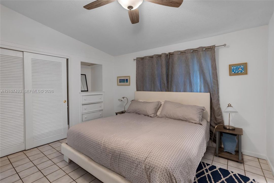 Main Apt, East side, Bedroom, Ceramic tile flooring, built-in recessed cabinetry, and ceiling fan with integrated lighting