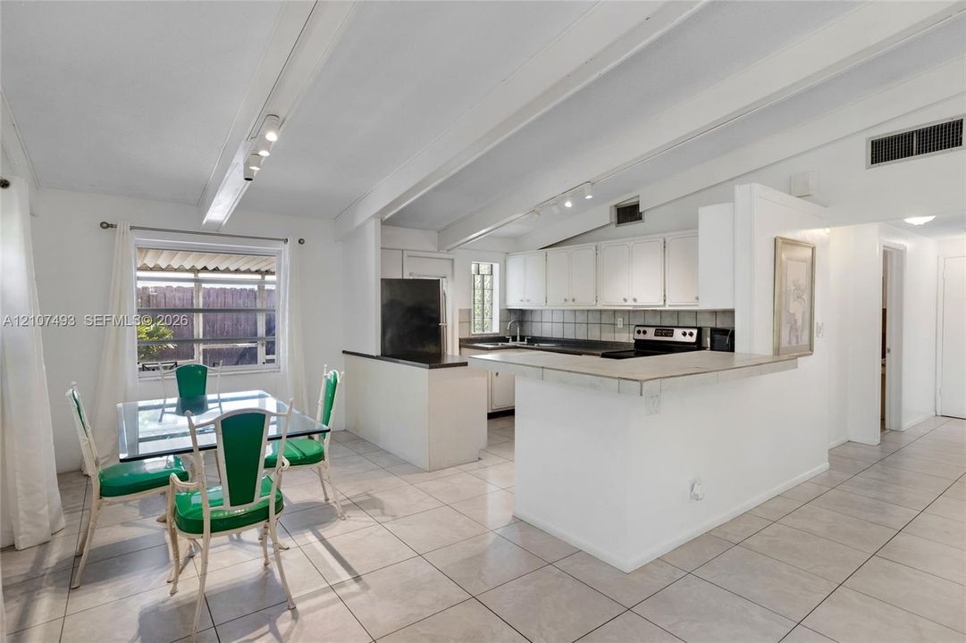 Main Apt, East side, Kitchen and dining area, Vaulted ceilings with exposed beams, tile flooring, breakfast bar, and track lighting