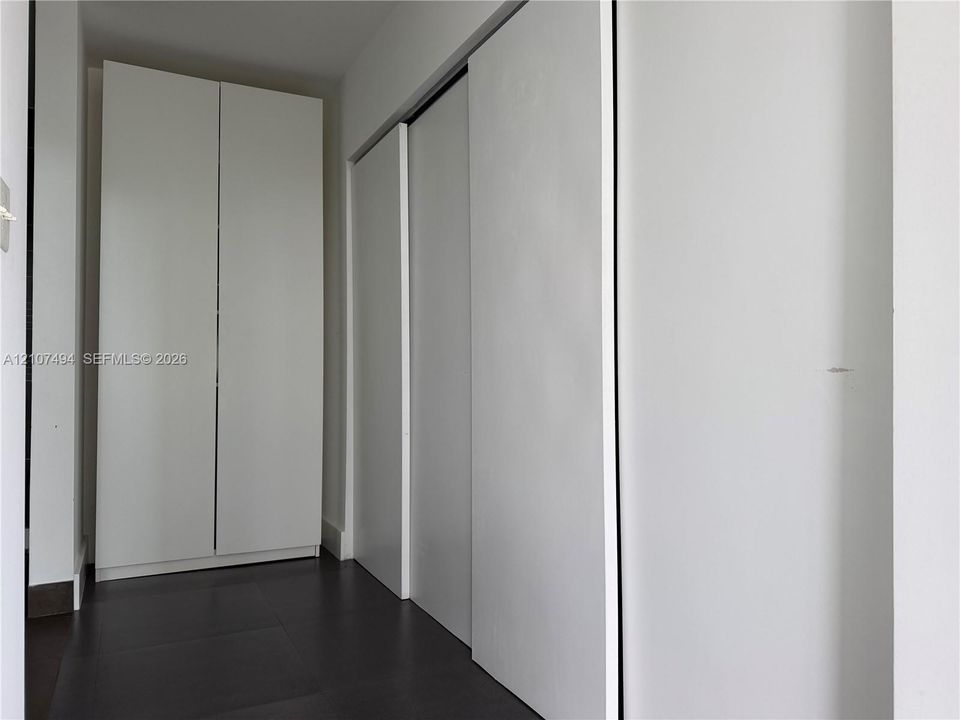 Floor-to-ceiling cabinetry with smooth white finish and dark tile flooring