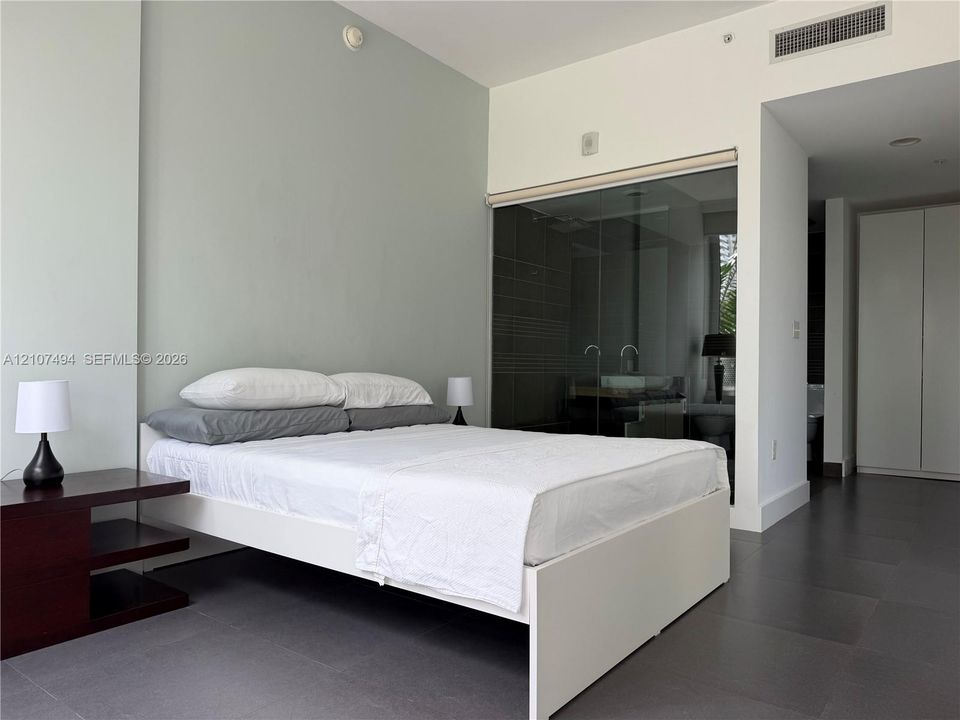 Interior room featuring large-format dark floor tiling, neutral wall finish, floor-to-ceiling glass wall enclosure, and integrated cabinetry