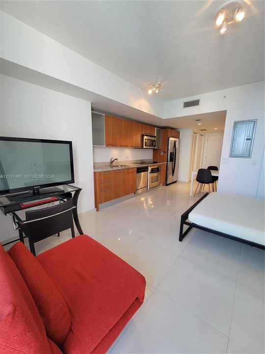 Kitchen featuring wood cabinetry, stone countertops, stainless steel appliances, and tile flooring