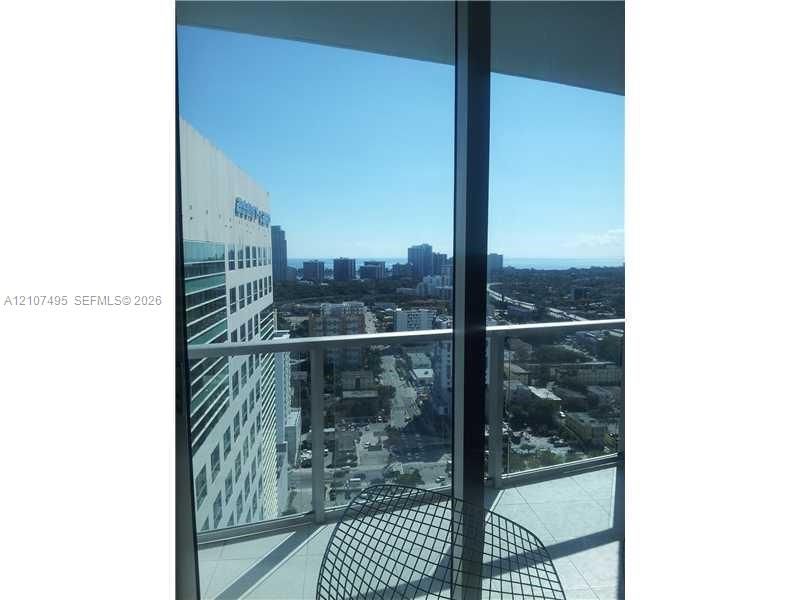 Covered balcony featuring floor-to-ceiling glass doors, a sleek metal railing, and light-toned tile flooring