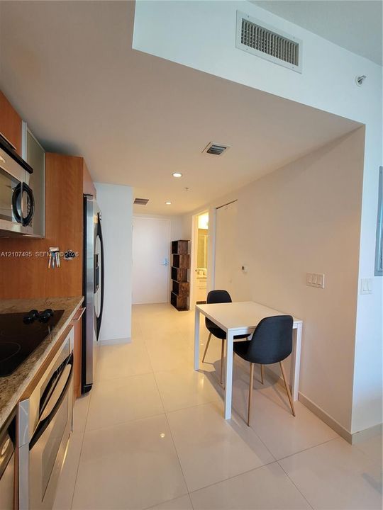 Kitchen featuring flat-panel wood cabinetry, stone countertops, stainless steel appliances, and large-format tile flooring