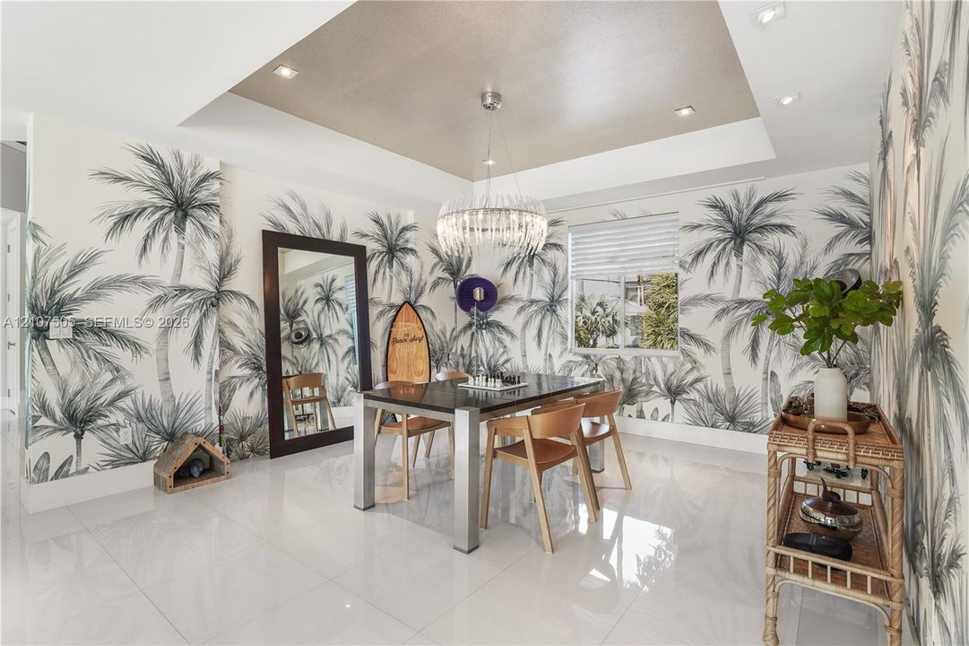 Tray ceiling featuring recessed lighting and a central tiered crystal chandelier, complemented by large-format polished tile flooring