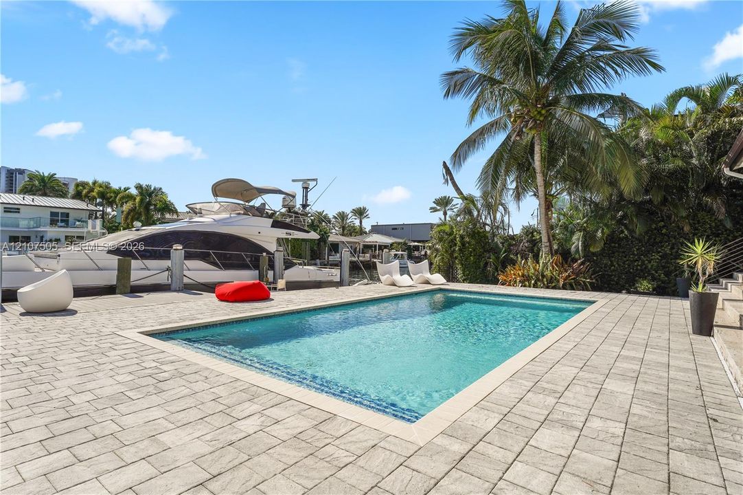 In-ground swimming pool with stone coping, concrete paver decking, and direct bulkhead water access