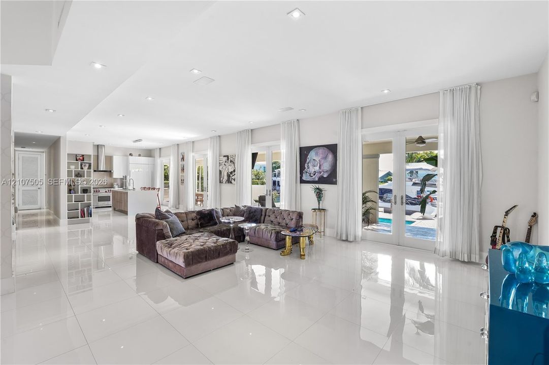 Open-concept interior featuring large-format polished tile flooring, recessed lighting, built-in shelving, and dual sets of glass-paned doors