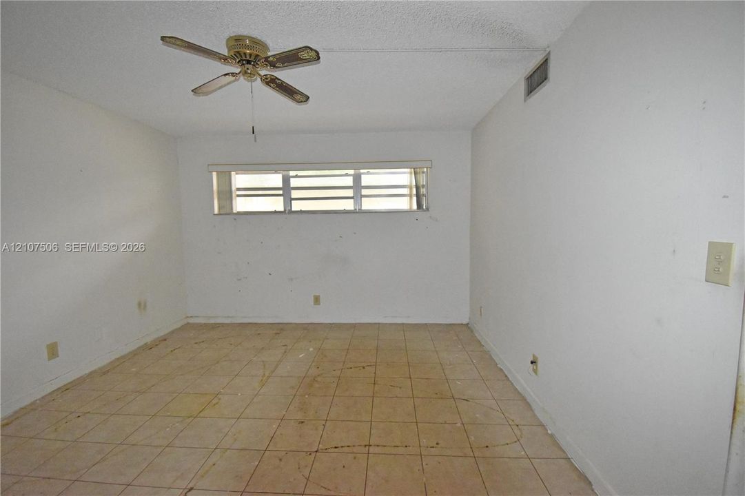 Interior room featuring tiled flooring, a horizontal slider window with window blinds, and a ceiling-mounted fan
