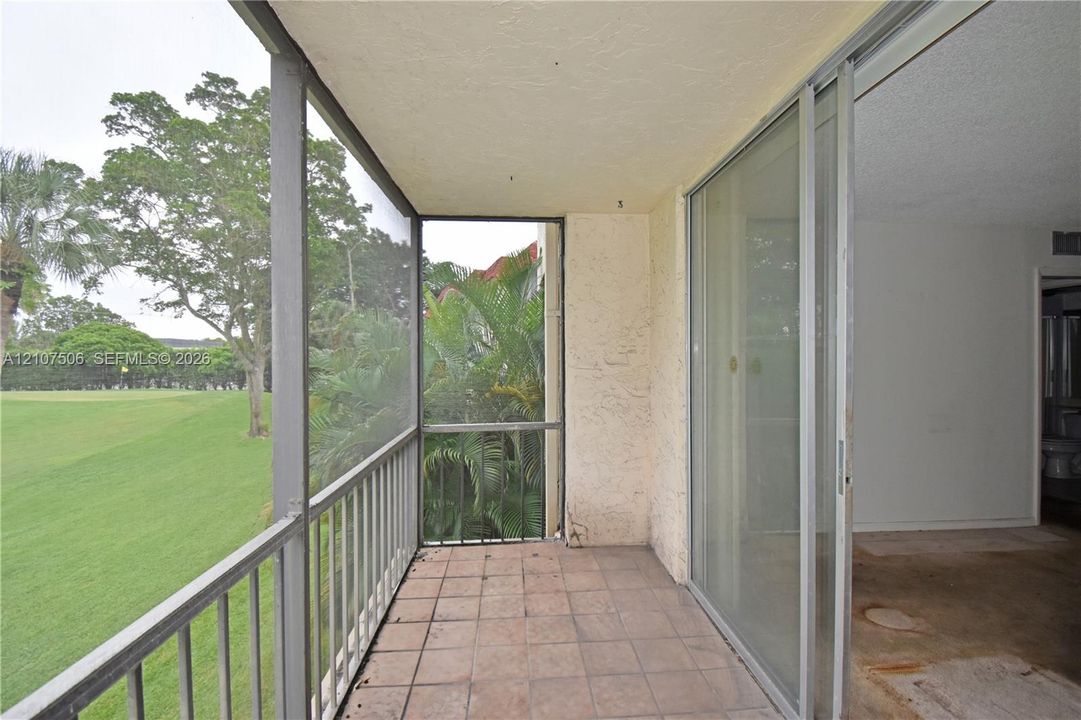Screened-in balcony featuring tile flooring, metal railings, and sliding glass doors