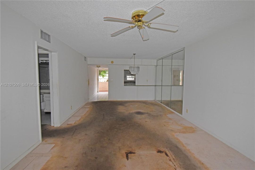 Interior space featuring full-wall mirrored closet doors, a ceiling-mounted fan, a crystal-style chandelier, and a pass-through opening