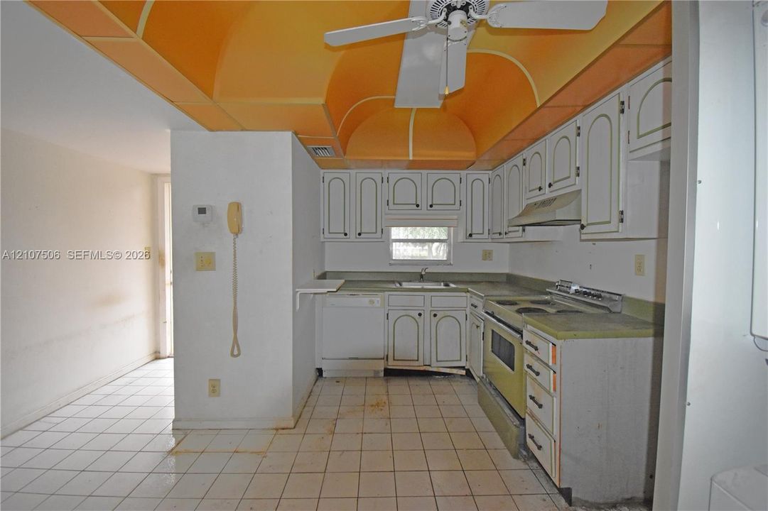 Kitchen featuring arched ceiling detail, white cabinetry with integrated hardware, ceramic tile flooring, and built-in appliances