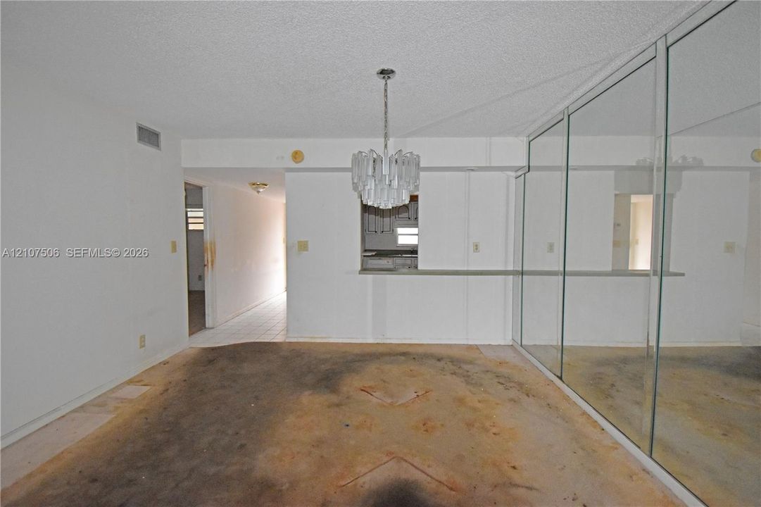 Interior space featuring a pass-through opening, a suspended multi-tiered chandelier, and a wall of floor-to-ceiling mirrored panels