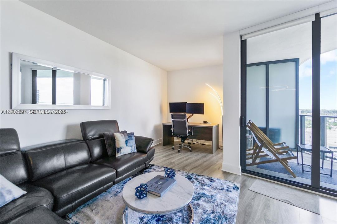 Wood-finish flooring, floor-to-ceiling glass paneling, and an external balcony featuring dark metal railings