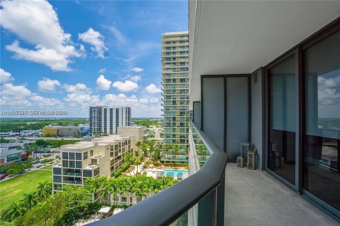 Covered balcony featuring concrete flooring, glass panel railings, and dark metal handrails