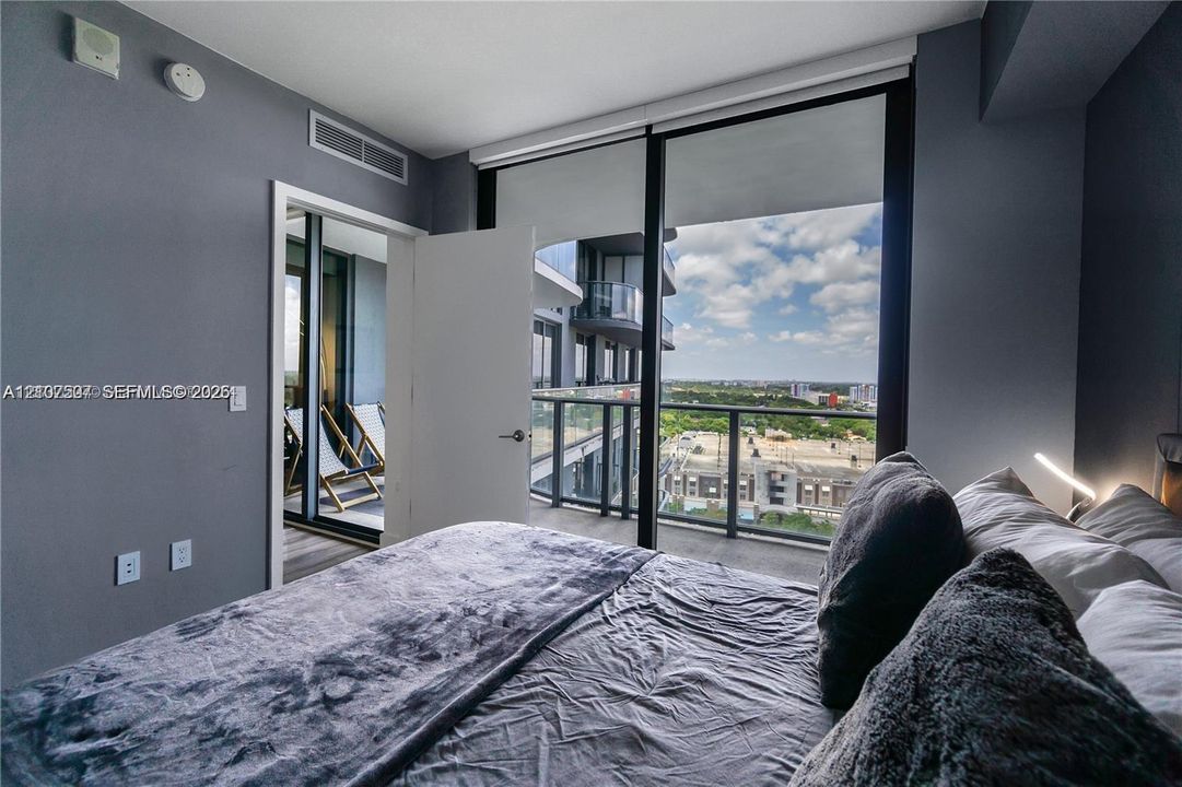 Floor-to-ceiling windows, private balcony with metal railing, and high-rise cityscape horizon