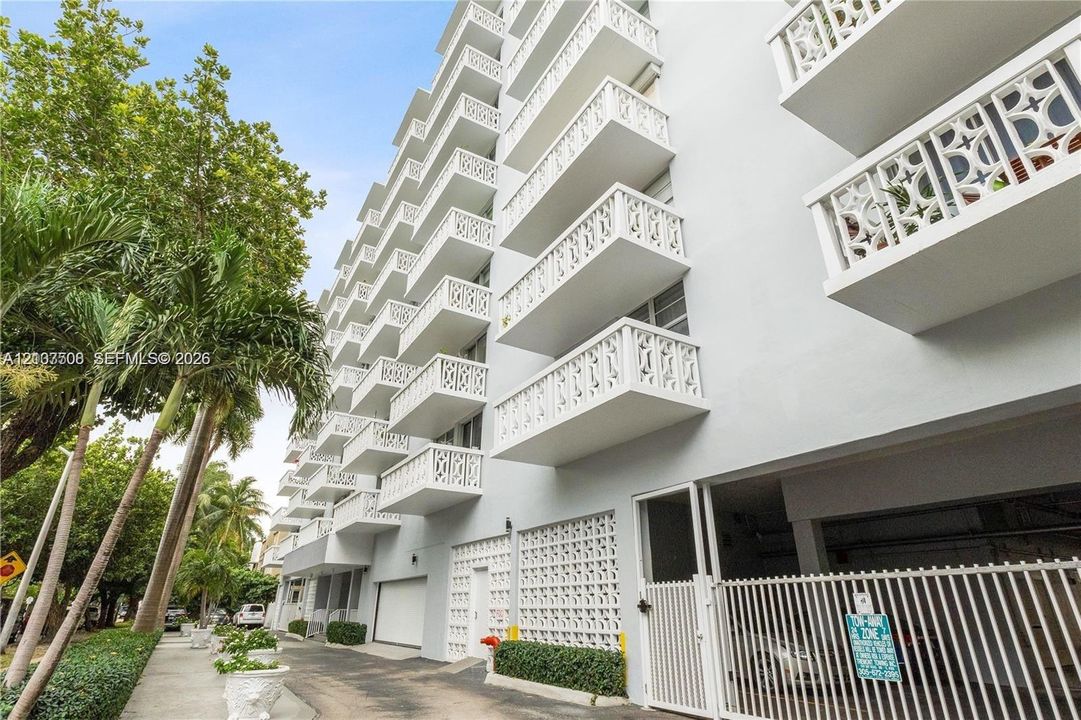 Multi-story exterior featuring tiered balconies with decorative lattice railings, structural concrete facade, and integrated ground-level parking