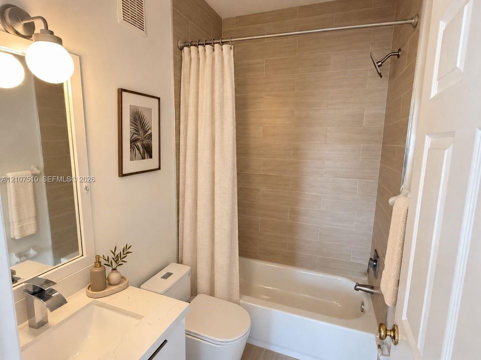Bathroom featuring a white vanity with a stone countertop, rectangular undermount sink, polished chrome faucet, tub-shower combination with horizontal tile surround, and dual-globe light fixture