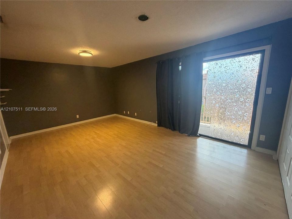 Wood-finish flooring, recessed ceiling lighting, and sliding glass door with textured privacy pane