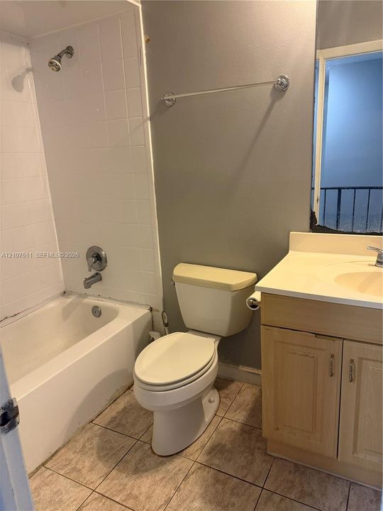 Bathroom featuring a built-in vanity with integrated basin, tiled tub surround, and ceramic tile flooring