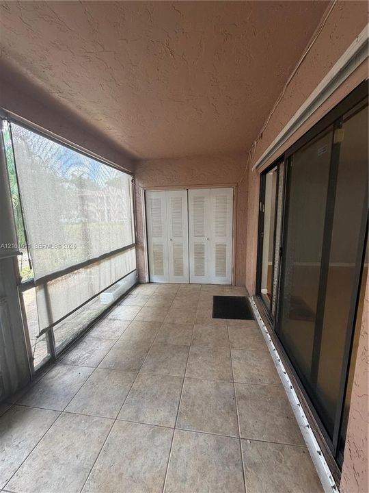 Screened-in patio featuring tile flooring, louvered-style closet doors, and sliding glass entry doors