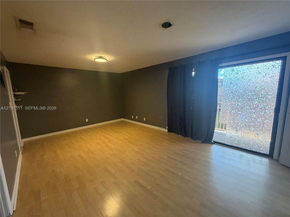 Interior room featuring wood-finish flooring, neutral wall tones, and glass sliding doors