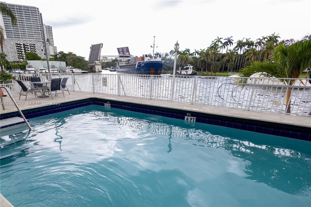 Swimming pool with tile surround, white metal railing, and concrete deck