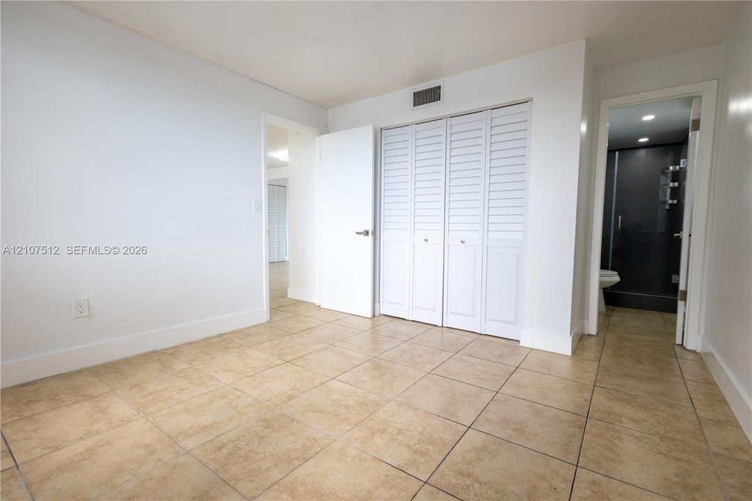 Neutral-toned tile flooring, built-in closet with louvered doors, and recessed ceiling lighting