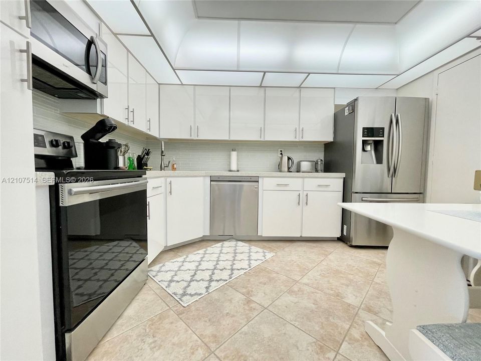 Kitchen featuring white cabinetry, stainless steel appliances, tile flooring, and integrated ceiling lighting