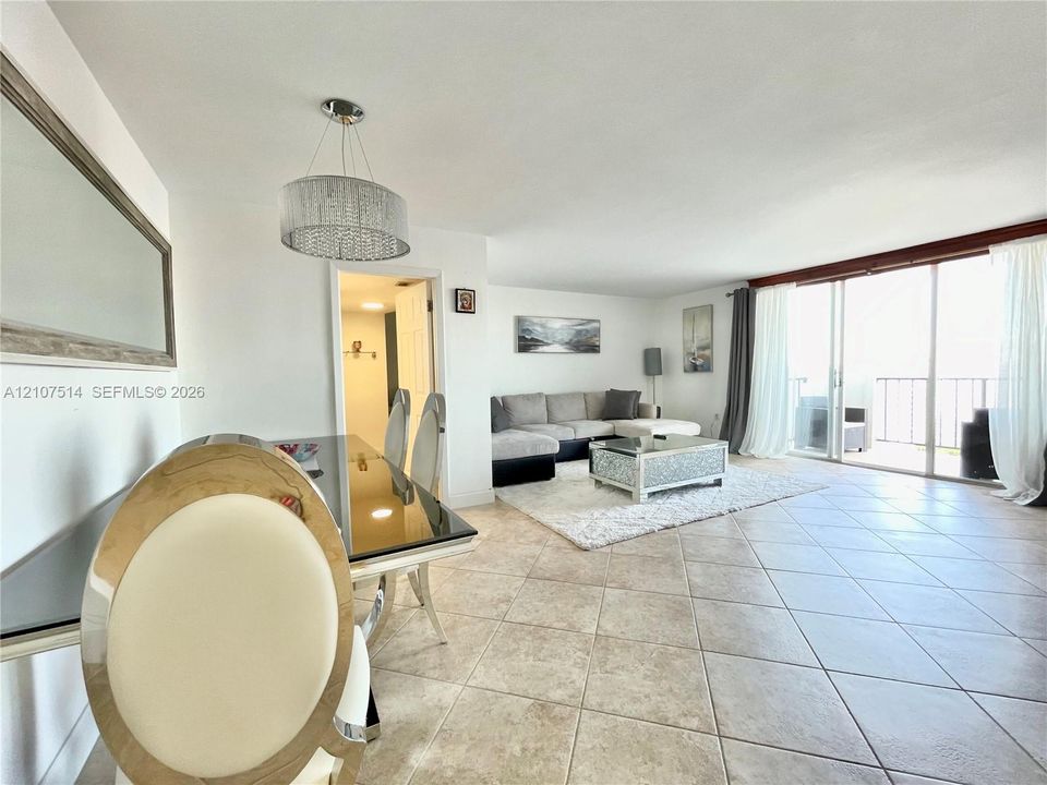 Open-concept interior featuring oversized floor tile, a drum-style pendant light fixture, and floor-to-ceiling sliding glass doors